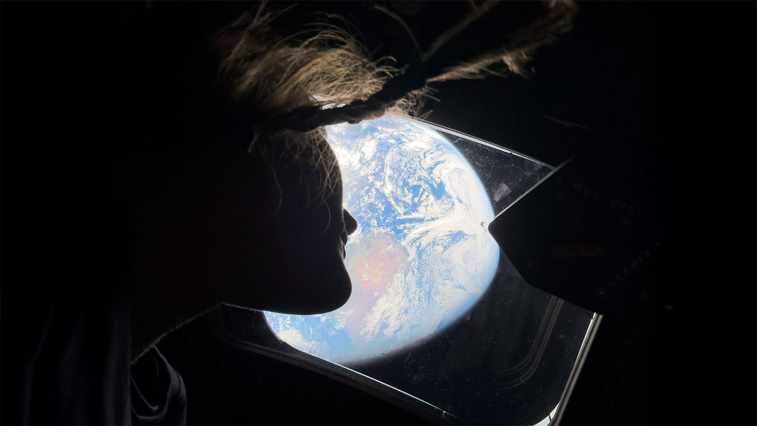NASA Artemis II astronaut Christina Koch looks out the Orion spacecraft window at Earth from lunar orbit